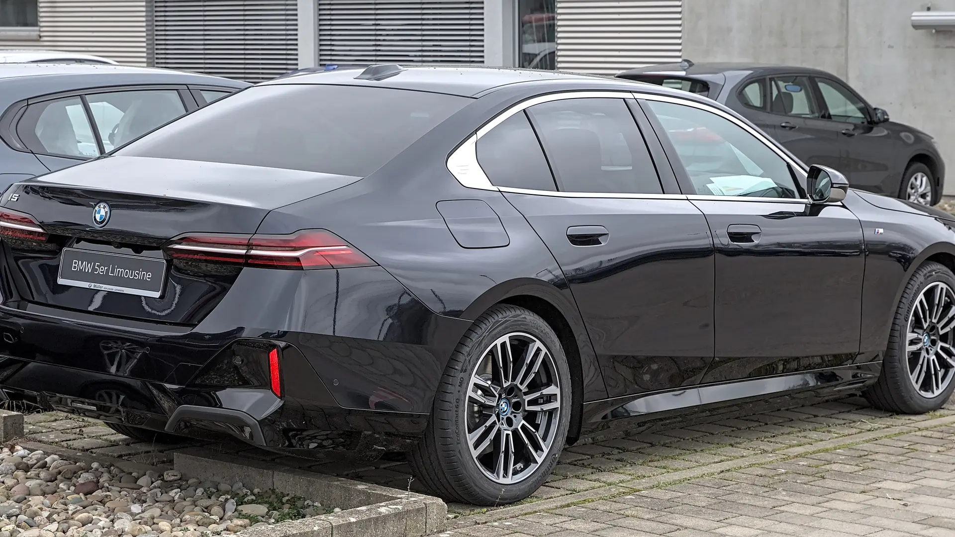 Een zwarte BMW i5, schuin van voren, op een parkeerplaats