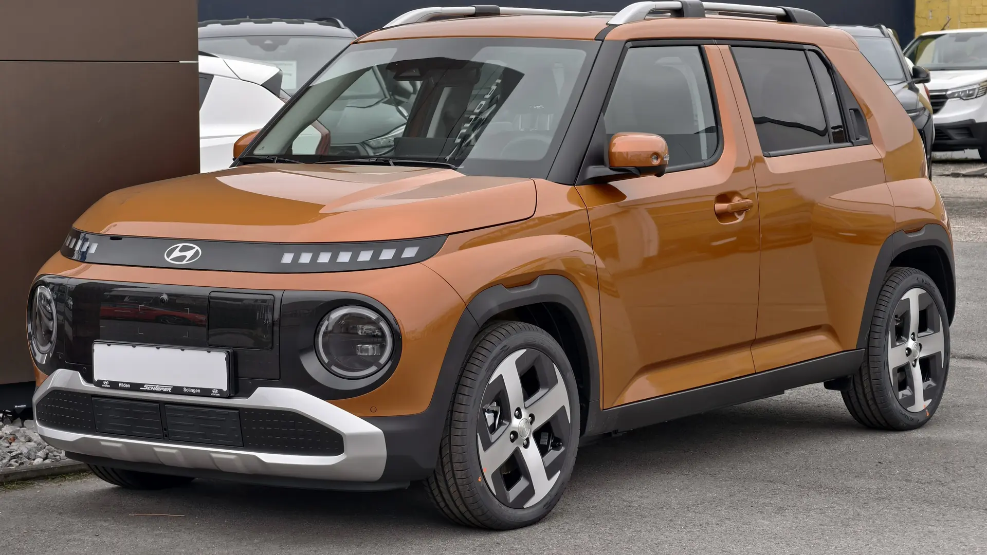Een koperkleurige Hyundai INSTER, schuin van voren, op een parkeerplaats
