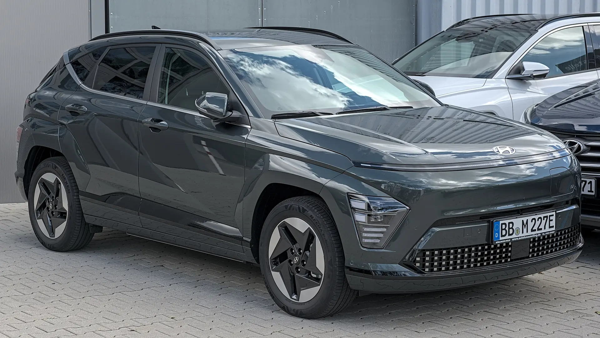 Een donkergrijze Hyundai KONA Electric, schuin van voren, op een parkeerplaats