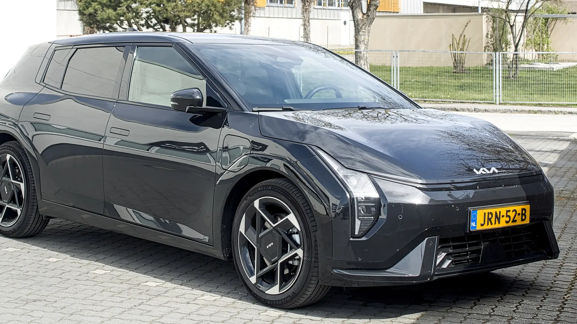 Een donkergrijze Kia EV4 met Nederlands kenteken, schuin van voren, op een parkeerplaats