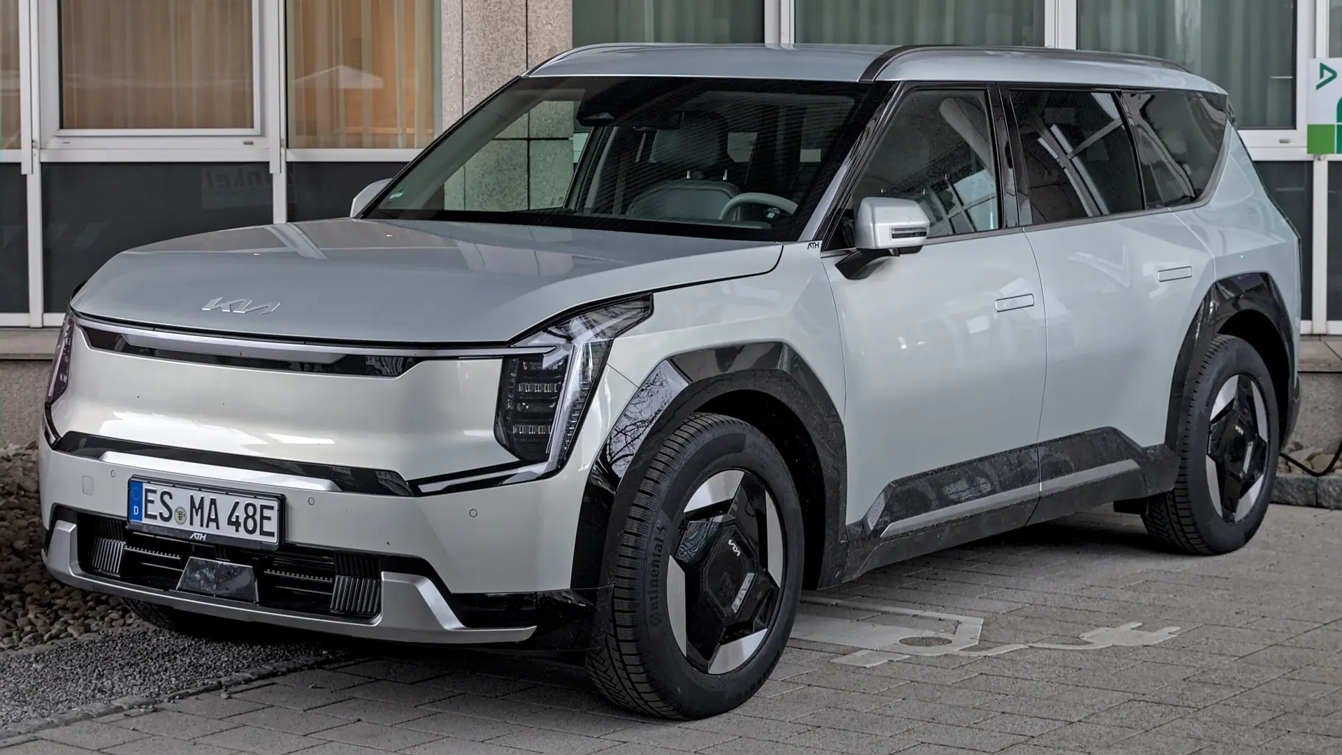 Een zilveren Kia EV9, schuin van voren, op een parkeerplaats