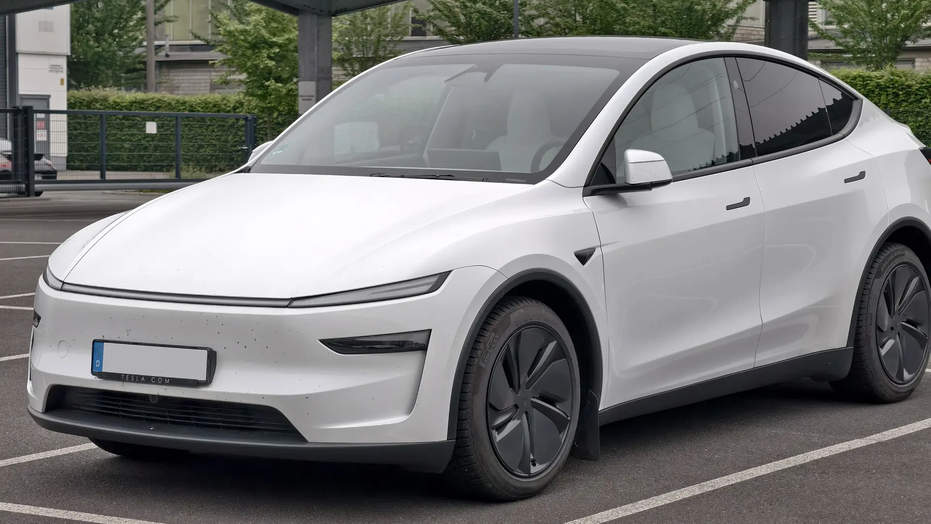 Een witte Tesla Model Y, schuin van voren, op een parkeerplaats