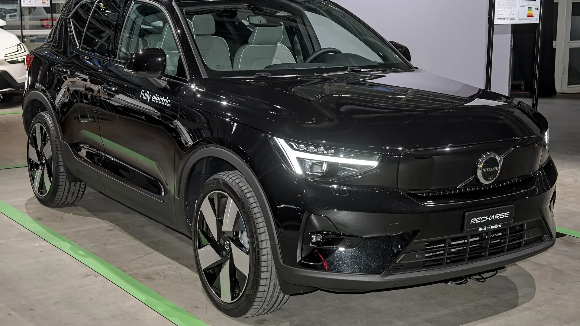Een zwarte Volvo EX40, schuin van voren, op een autobeurs