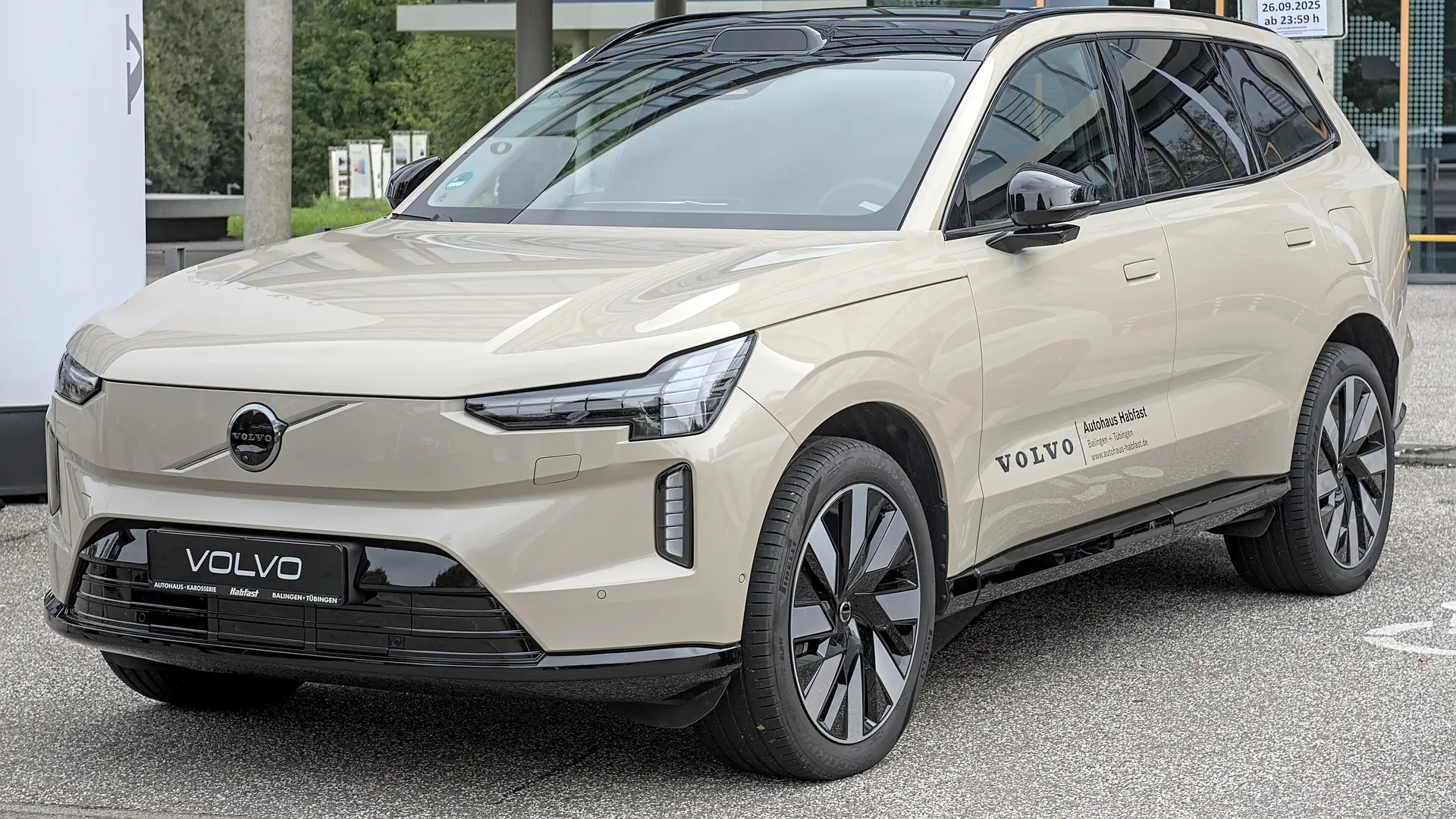 Een beige Volvo EX90, schuin van voren, op een autobeurs